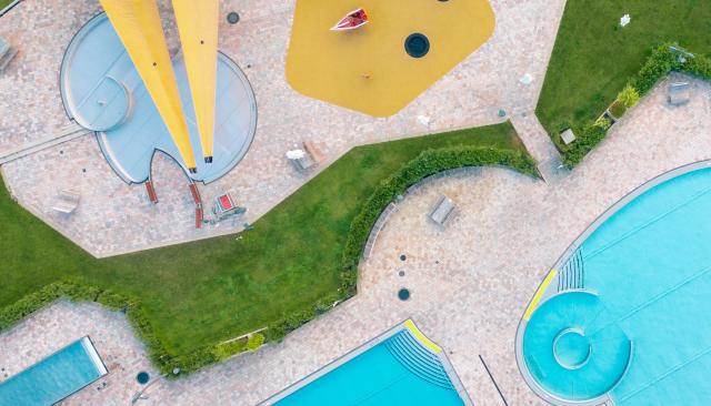 Blick von oben auf mehrere Schwimmbecken und Kleinkinderbereich